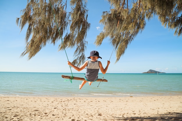 Belle photo d'un bébé assis sur un pendule sur la plage