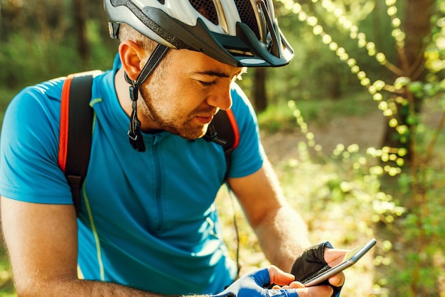 Belle photo d'un cycliste à vélo utilisant le navigateur sur son appareil, explorez la carte et recherchez les coordonnées GPS sur mobile tout en faisant du vélo dans les montagnes Voyage sports mode de vie actif et technologie moderne