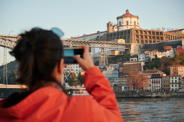 Une belle photo d'une fille espagnole prenant une photo d'un paysage urbain à porto