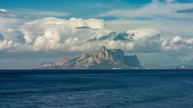 Belle photo d'une mer et de la montagne rocheuse au loin avec des nuages dans le ciel