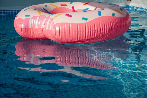 Belle piscine bleue rafraîchissante avec beignet gonflable rose