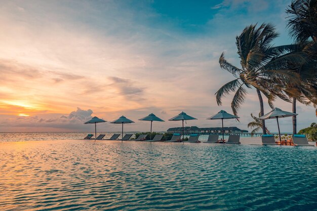 Belle piscine et ciel coucher de soleil. Paysage de plage tropicale luxueux, chaises longues, transats