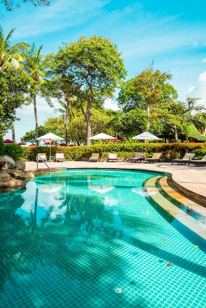 Belle piscine tropicale avec parasols et chaises longues