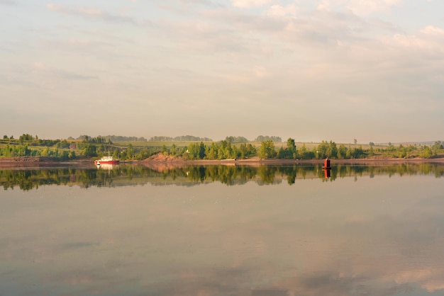 Belle plage de paysage avec des arbres verts et un bateau sur la rivière