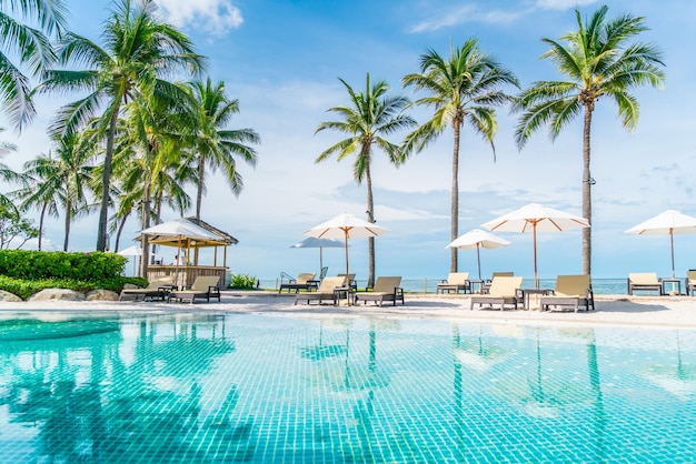 Belle plage tropicale et mer avec parasol et chaise autour de la piscine de l'hôtel pour les voyages et les vacances