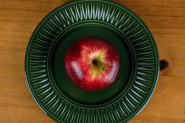 belle pomme servie dans une assiette vert foncé sur la photo de la table en bois avec un espace pour le texte