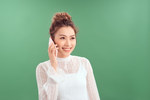 Belle de portrait jeune femme asiatique parler téléphone intelligent sur fond vert.