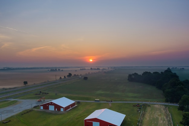 Belle prairie de paysage de village brumeux avec brouillard lever de soleil tôt le matin avec vue panoramique