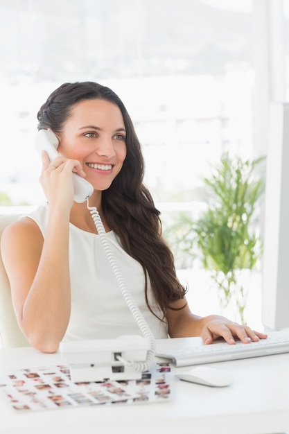 Belle rédactrice au téléphone à son bureau