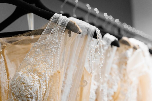 Belle robe de mariée crème blanche sur des cintres dans un salon de mariage. Pendentifs de perles et cristaux sur les manches d'une robe de mariée.