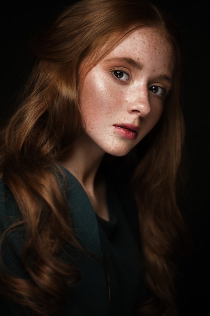 Belle rousse avec des cheveux parfaitement bouclés et un maquillage classique