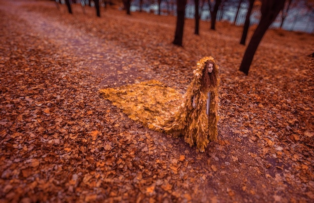 Belle rousse comme un automne en manteau de feuilles dans la forêt