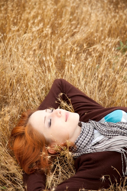 Belle rousse couchée sur l&#39;herbe jaune. Temps de saison d&#39;automne