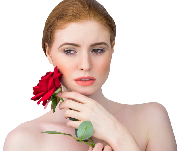 Belle rousse posant avec une rose rouge