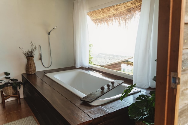 Belle salle de bain confortable et confortable sur plateau sur baignoire près de la fenêtre Le bain avec de la mousse se remplit d'eau Se détendre dans un hôtel spa de luxe à Bali