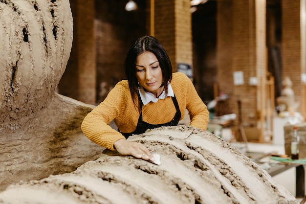 Belle sculptrice professionnelle de femme d'âge moyen travaillant sur une magnifique sculpture.