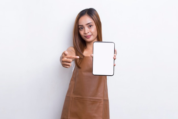 Belle serveuse asiatique de barista démontrant le téléphone portable sur le fond blanc