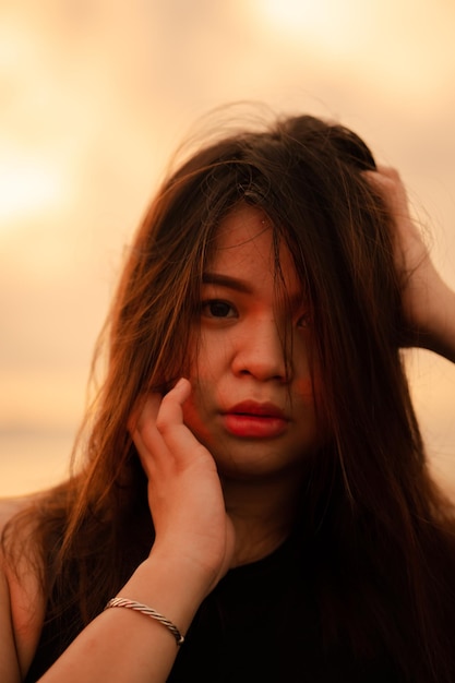 Une belle et sexy femme asiatique avec une expression faciale qui a l'air foirée en se tenant debout sur la plage