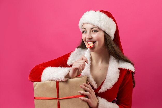 Belle et sexy femme portant le costume de père Noël. La fille tient des cadeaux de Noël.