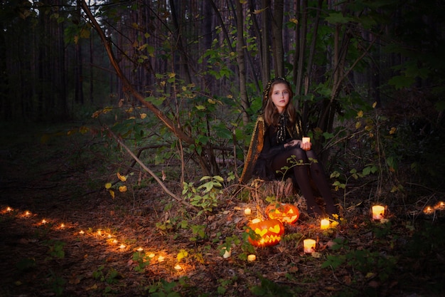 Belle sorcière avec une citrouille dans la forêt magique