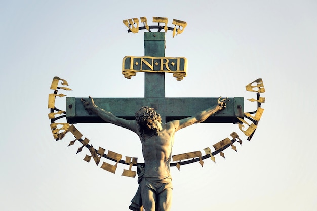 Belle statue en bronze de la crucifixion de Jésus-Christ au lever du soleil Statuaire de la Sainte Croix avec Calvaire Pont Charles Prague République tchèque journée ensoleillée ciel clair
