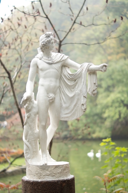 Belle statue de jardin classique d'un dieu grec ou romain iwth superbe physigue nue et vêtements fluides debout devant un lac