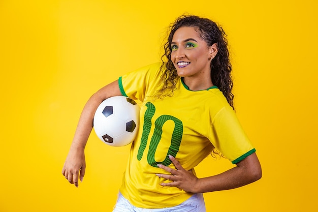 Belle supporter brésilienne avec un ballon de football sur fond jaune coupe du monde 2022