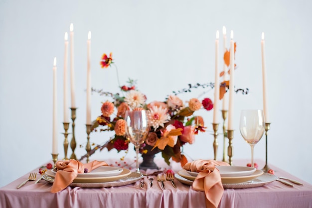 Belle table avec des fleurs d'automne des serviettes orange et roses et des bougies allumées Concept de mariage d'automne