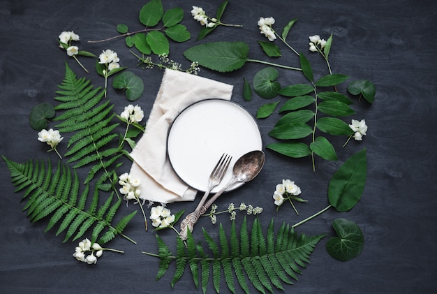 Belle table printanière boho mise en place avec une décoration de fleurs et de plantes sauvages. Photo vue de dessus à plat à la mode.