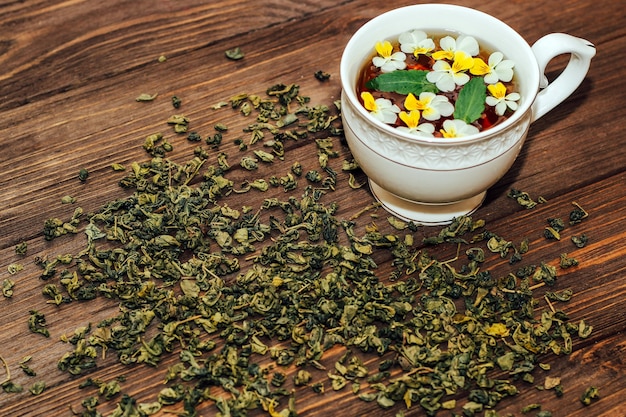 Une belle tasse blanche avec une bordure dorée décorée de fleurs, de tisane verte saine. Conception de compte d'entreprise.