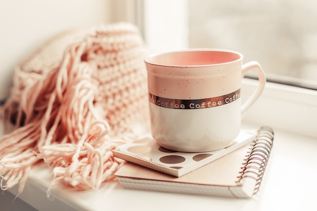 Belle tasse de thé rose avec carnet et écharpe tricotée