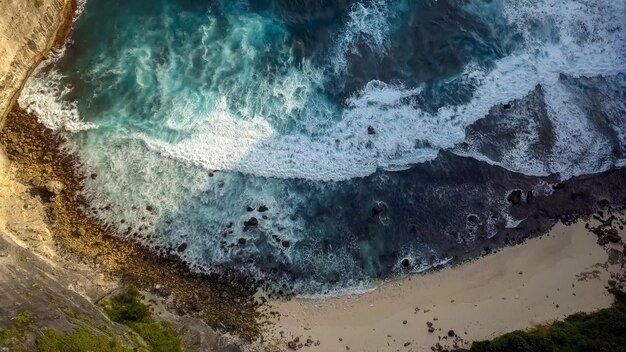 Photo belle texture des vagues de l'océan sombre avec de la mousse blanche drone filmant des vagues déferlantes dans l'océan indien sur l'île de nusa penida vue à vol d'oiseau grande vague dans la capitale bali surfig