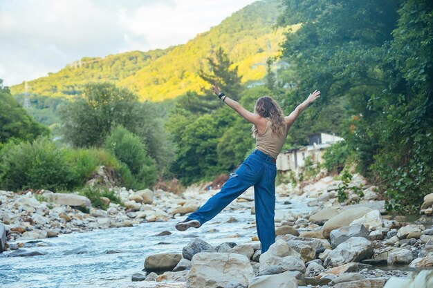 une belle touriste aime la vie près d'une rivière de montagne sur le fond elle a des montagnes