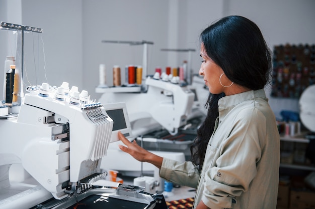 La belle travailleuse est dans l'usine de couture près de la machine.