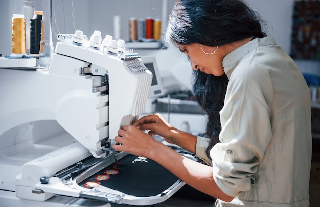 La belle travailleuse est dans l'usine de couture près de la machine.