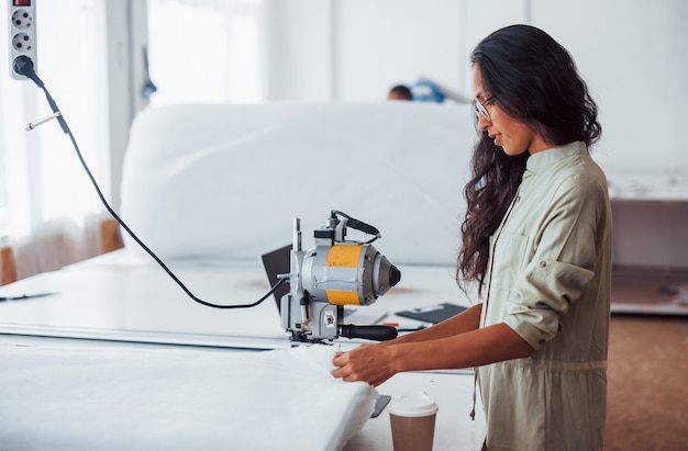 Belle travailleuse avec des lunettes est dans l'usine de couture.