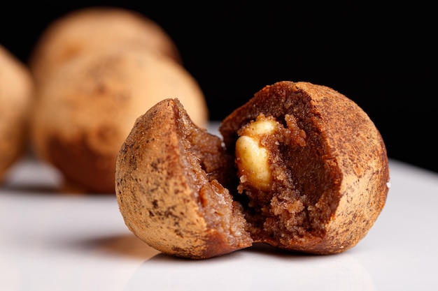 Belle truffe de bonbon avec une noix à l'intérieur d'un plat blanc sur un fond noir