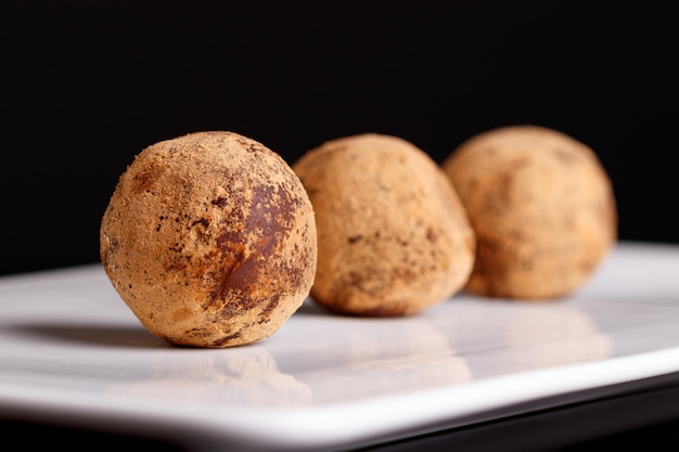 Belle truffe de bonbon d'un plat blanc sur un fond noir