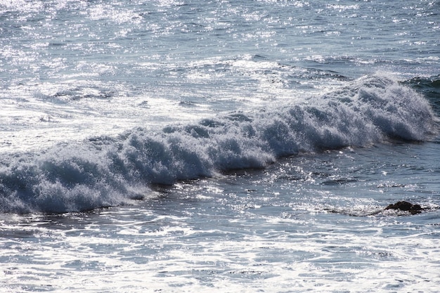 Belle vague bleue éclaboussant de mousse blanche dans la mer tropicale ensoleillée