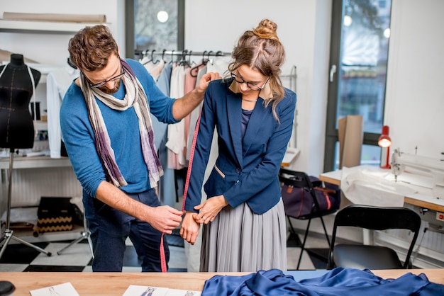 Belle veste de mesure sur mesure sur la cliente debout au studio plein d'outils et d'équipements de couture