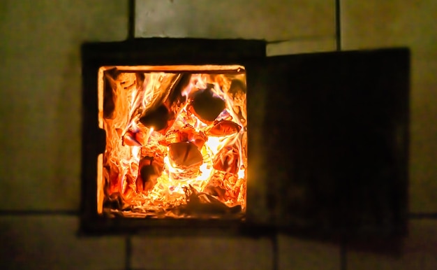 Belle vieille cheminée avec un feu de flamme léger pour chauffer la pièce du bâtiment ancienne cheminée composée de bûches de bois de chêne épaisses dans un feu de flamme chaude feu de flamme vif dans une vieille cheminée en fer d'un arbre en tranches