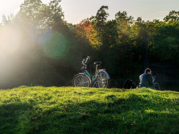 Belle vue d'automne avec un cycliste se reposant sur une colline sur fond de lumière du soleil.