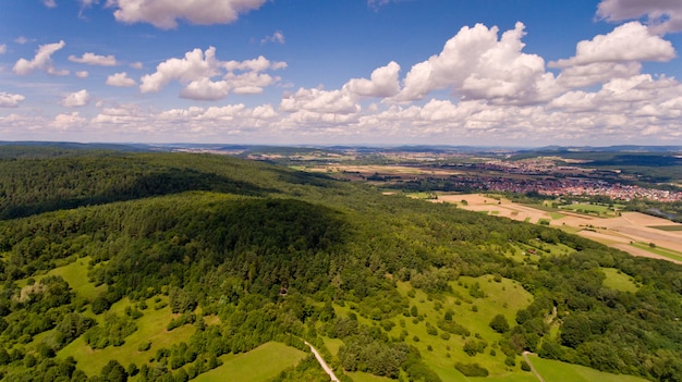 Belle vue sur une colline avec une forêt verte et un ciel bleu avec des nuages blancs. Vue aérienne.