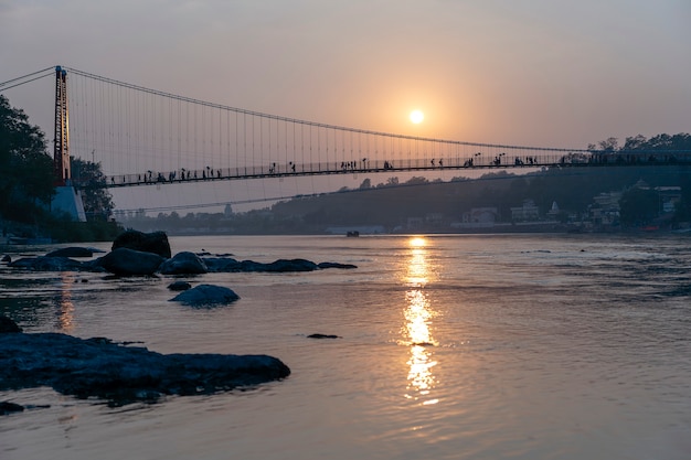 Belle vue sur la digue et le pont de l'eau du Gange au coucher du soleil. Rishikesh, Inde