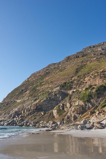 Belle vue sur un paysage naturel avec le sable de la mer et un fond de ciel bleu Cadre extérieur naturel de la plage et des montagnes verdoyantes Environnement isolé à l'extérieur près de l'eau de l'océan