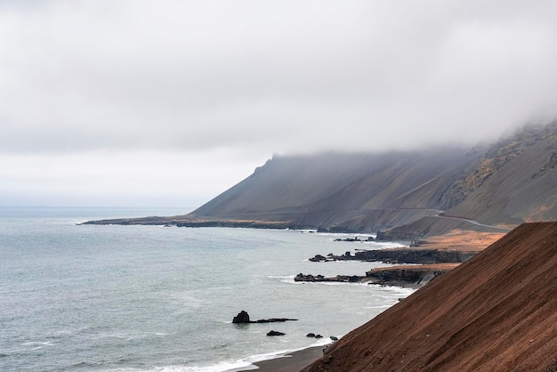 Belle vue sur la pente brune raide par plage contre ciel nuageux par temps de brouillard