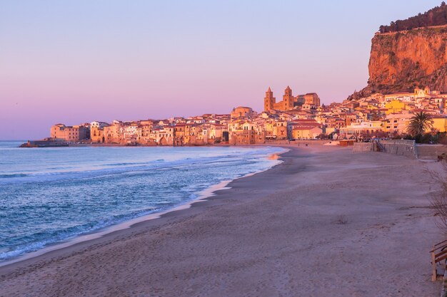 Belle vue sur la plage vide, la cathédrale de Cefalu et la vieille ville de la ville côtière de Cefalu au coucher du soleil rose, Sicile, Italie