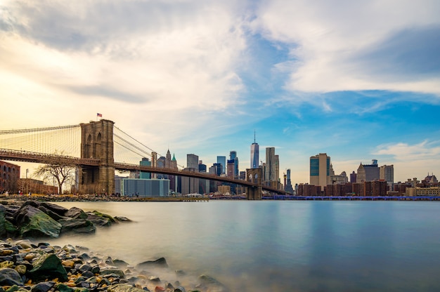 Photo belle vue sur le pont de brooklyn et manhattan inférieur de la ville de new york au crépuscule. centre-ville de manhattan inférieur de la ville de new york et de la rivière hudson lisse avec lumière du coucher du soleil.