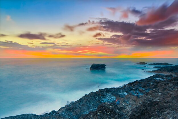 belle vue avec des rochers et des collines pendant l'incroyable coucher de soleil sur la plage de menganti java central