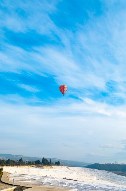 Une belle vue sur les travertins à Pamukkale avec des montgolfières dans les airs